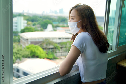 Social distancing concept. Young Asian lady with face mask staying and working at home during quarantine period. Self quarantine. Covid 19 outbreak pandemic. Free Download Social distancing concept. Young Asian lady with face mask staying and working at home during quarantine period. Self quarantine. Covid 19 outbreak pandemic. - GFXLoad