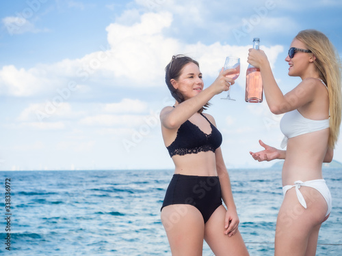 young brunette caucasian woman and friend drinking wine on yacht in sea with blue sky copy space background pattaya Thailand