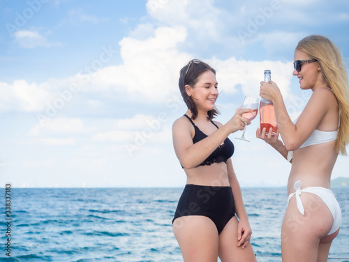 young brunette caucasian woman and friend drinking wine on yacht in sea with blue sky copy space background pattaya Thailand