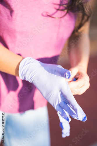 Girl on the street is holding medical gloves. the girl is going to put on medical gloves during the coronavirus pandemic in the street