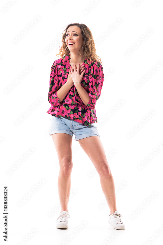 Fototapeta premium Amazed touched young woman with caring heartwarming expression looking up with hands on heart. Full body isolated on white background. 