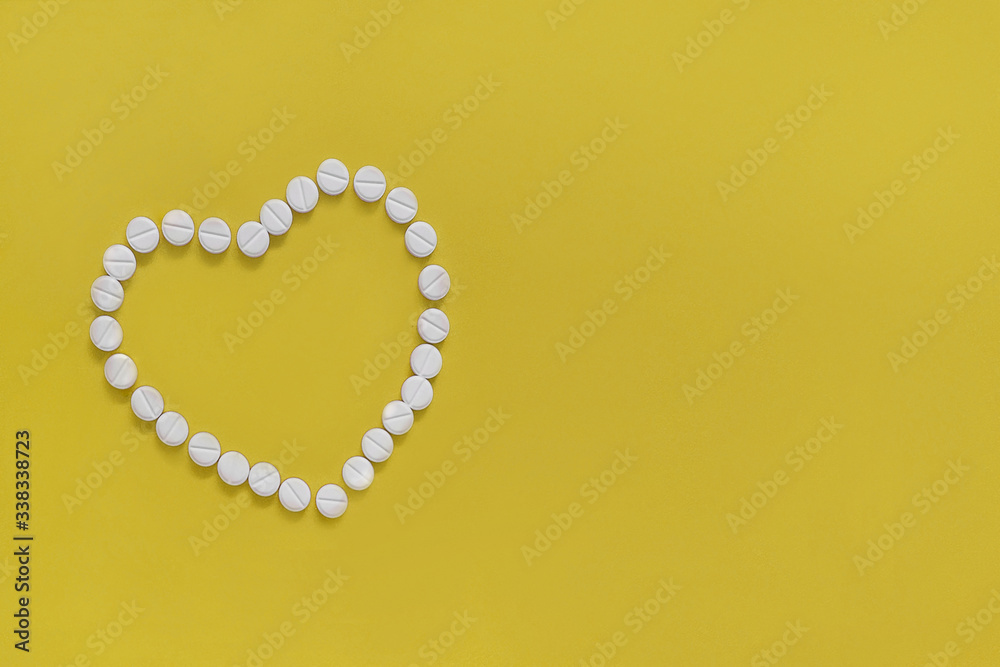 The heart made of tablets and pills on yellow background The heart made of tablets and pills on yellow background