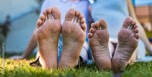 Romantic young couple kissing in the garden. Family feet in focus. Feet of a young couple lying on grass at the park.