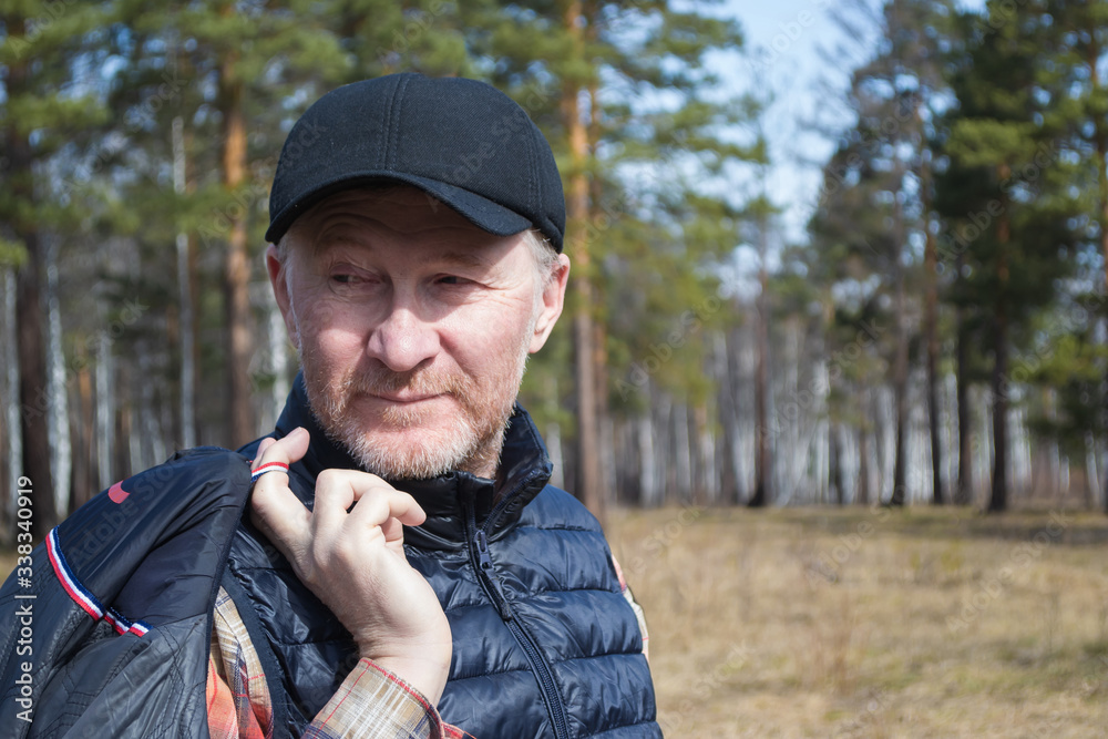 A middle-aged man in a cap, smiling, walks in the park.