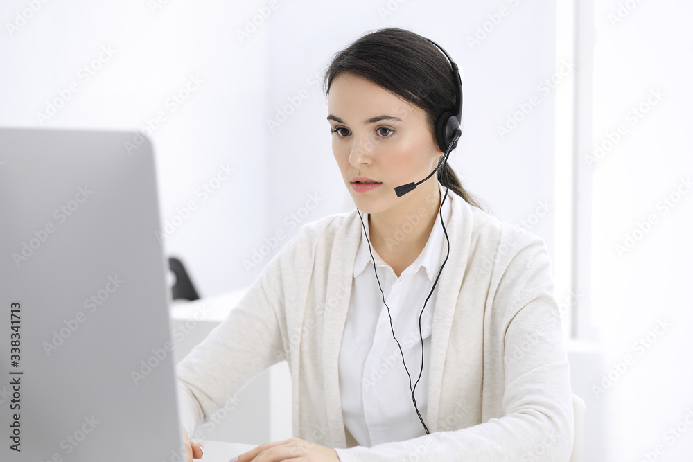 Call center. Casual dressed woman sitting in headset at customer service office. Group of operators at work. Business concept Call center. Casual dressed woman sitting in headset at customer service office. Group of operators at work. Business concept
