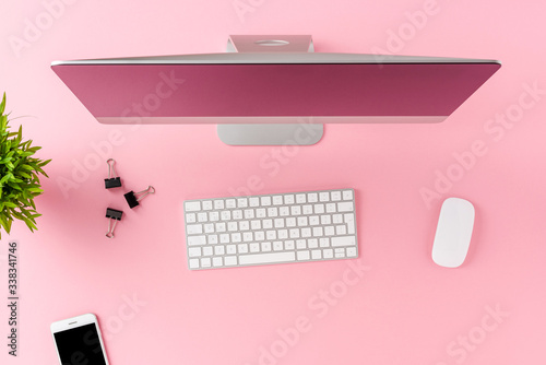 Overhead shot of computer with business accessories on pink desktop. Modern workspace concept. Flat lay