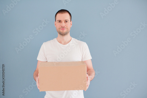 Caucasian man with cardboard box on a blue background