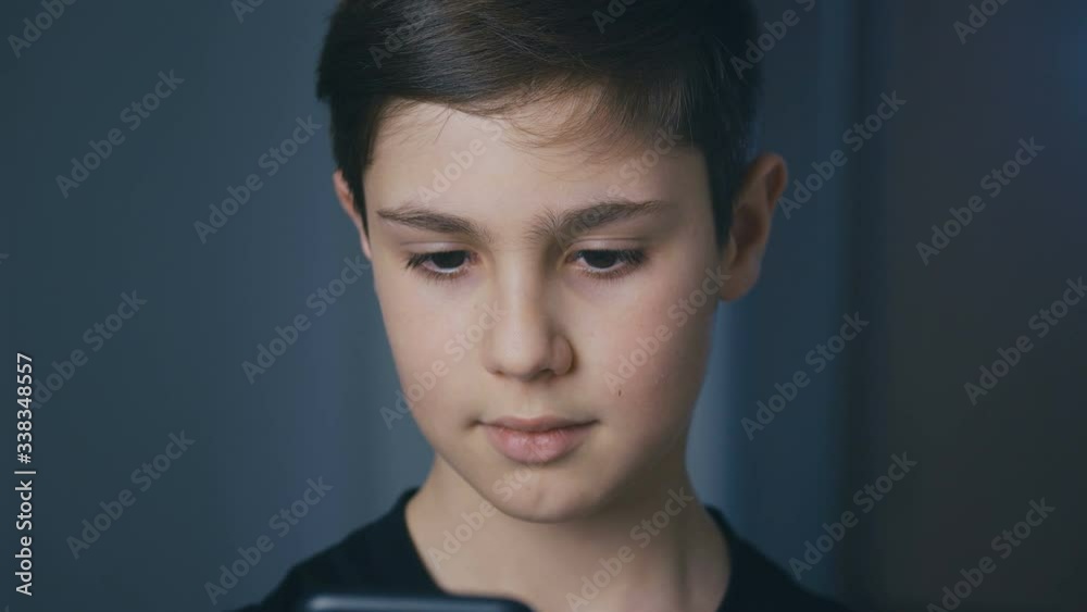 Young boy playing on his smartphone. Kid playing mobile game on smart phone. Child playing video game at home Young boy playing on his smartphone. Kid playing mobile game on smart phone. Child playing video game at home