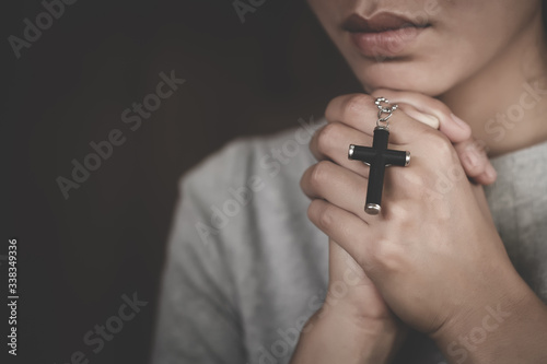 Hand of woman while praying for christian religion, Casual woman praying with a cross, Religion concept.