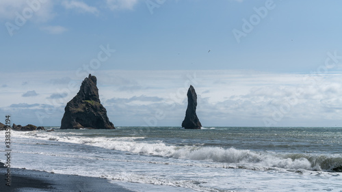The black sand beach of Reynisfjara with rock formations in the sea, southern coast of Vik, Iceland © CanYalicn
