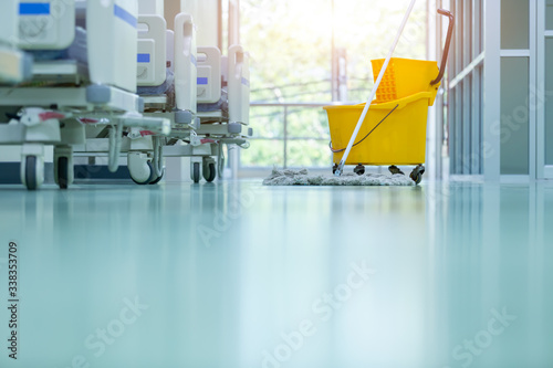 Obraz na płótnie Cleaner using mops, cleaner with mop and uniform cleaning hall floor, hospital cleaning floor with mop in patient room the hospital epoxy floor