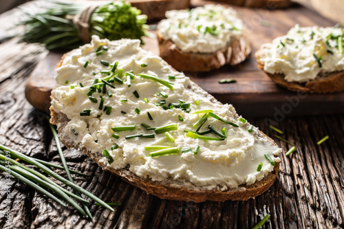 Close-up of bread slice with traditional Slovak bryndza spread made of sheep cheese with freshly cut chives placed on rustic wood photo