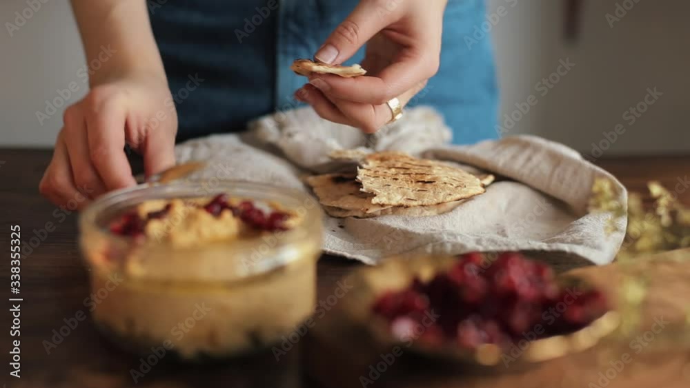 A young girl cooked home-made traditional hummus in her kitchen and smears it on pieces of pita. Close-up A young girl cooked home-made traditional hummus in her kitchen and smears it on pieces of pita. Close-up