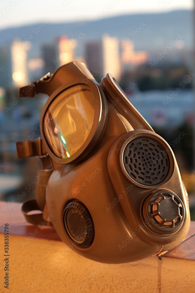 Military grade gas mask, model M10, sunbathing on in morning cityscape in background. Stock Photo Adobe Stock