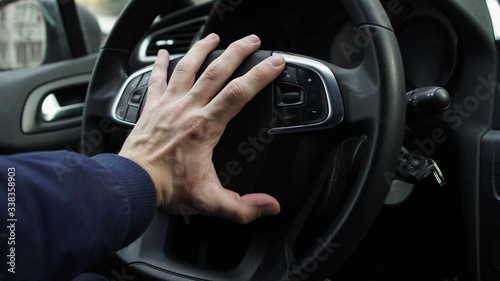 Hand of the car driver on the steering wheel horn, beeping