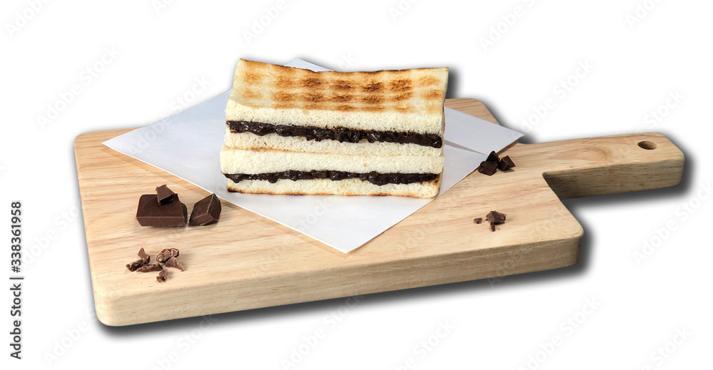 The delicious and delicious chocolate chip sandwiches are smeared on the toasted golden toast. They are arranged on baking paper and wooden texture cutting boards. They are presented with a brown back