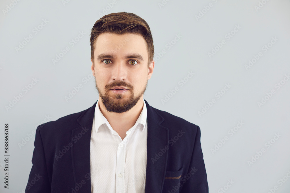 Puzzled insecure man in casual jacket on a gray background. Expression of emotion