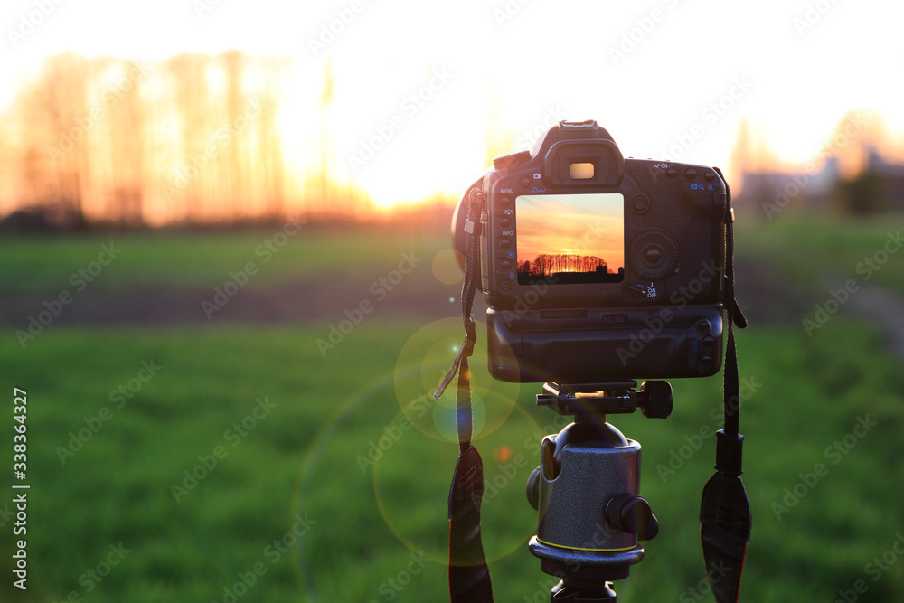 Aparat fotograficzny z krajobrazem zachodzącego słońca na obszarze wiejskim. - obrazy, fototapety, plakaty 