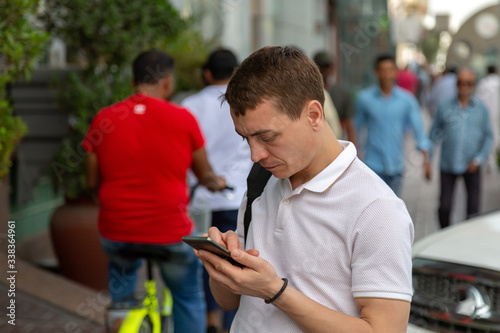 Caucasian male tourist communicates on social networks on a smartphone while standing on a street in the Muslim district of the city.