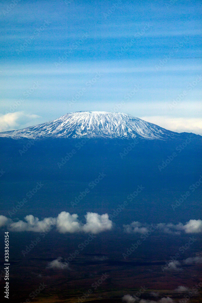 Aerial image of Mount Kilimanjaro, Africa's highest mountain, with snow and white puffy clouds from Kenya