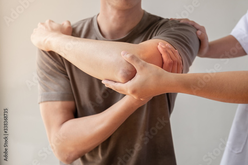 Female physiotherapists provide assistance to male patients with elbow injuries examine patients in rehabilitation centers Fototapet
