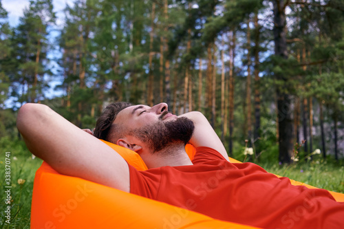 Enjoying life. A young man lies in a bivouac in the forest., relaxation, vacations, lifestyle concept © Aleksandr Rybalko