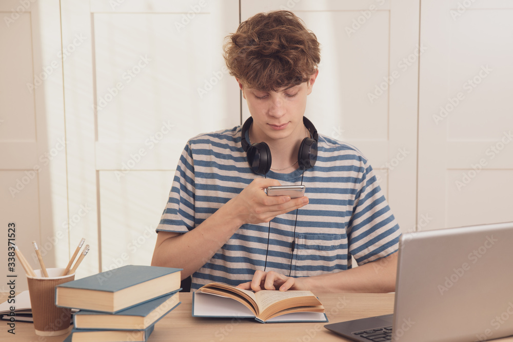 Teenager takes pictures of his notes by phone and sends them to classmates, learns using the laptop, phone and tablet.Distance learning because of the epidemic coronavirus Teenager takes pictures of his notes by phone and sends them to classmates, learns using the laptop, phone and tablet.Distance learning because of the epidemic coronavirus