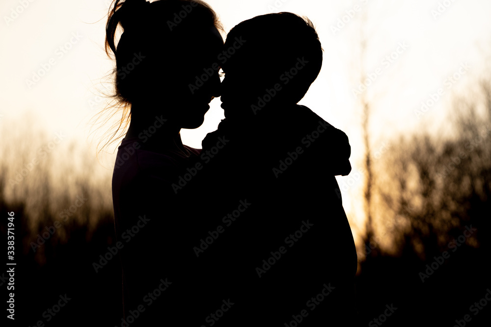Silhouette of a mother and son playing outdoors at sunset. Mother's day concept