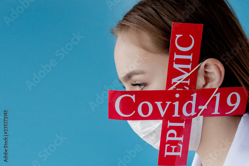 Doctor woman with surgical mask pointing to red paper with mesaage Coronavirus on blue background. World Health Organization WHO introduced new official name for Coronavirus disease named COVID-19 photo