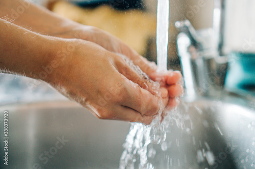 Woman washing her hands with soap in a hygienic way in her home sink. Kitchen
