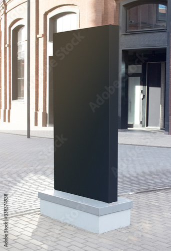 Blank black vertical pylon stand mockup brick building, side view photo