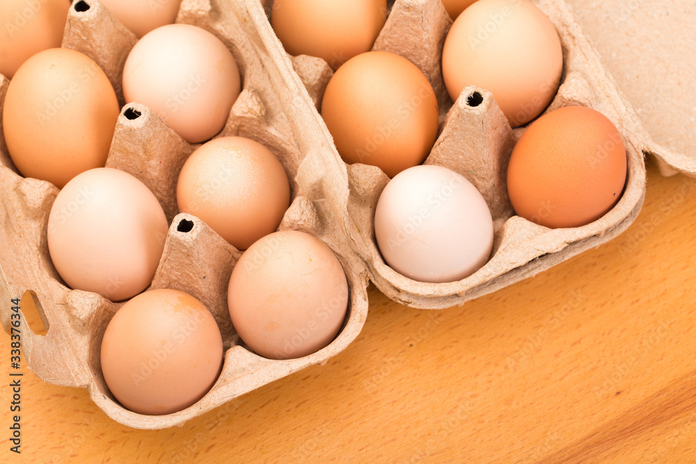 brown chicken eggs in an open cardboard box with eggs on a wooden table. Natural healthy food. brown chicken eggs in an open cardboard box with eggs on a wooden table. Natural healthy food.