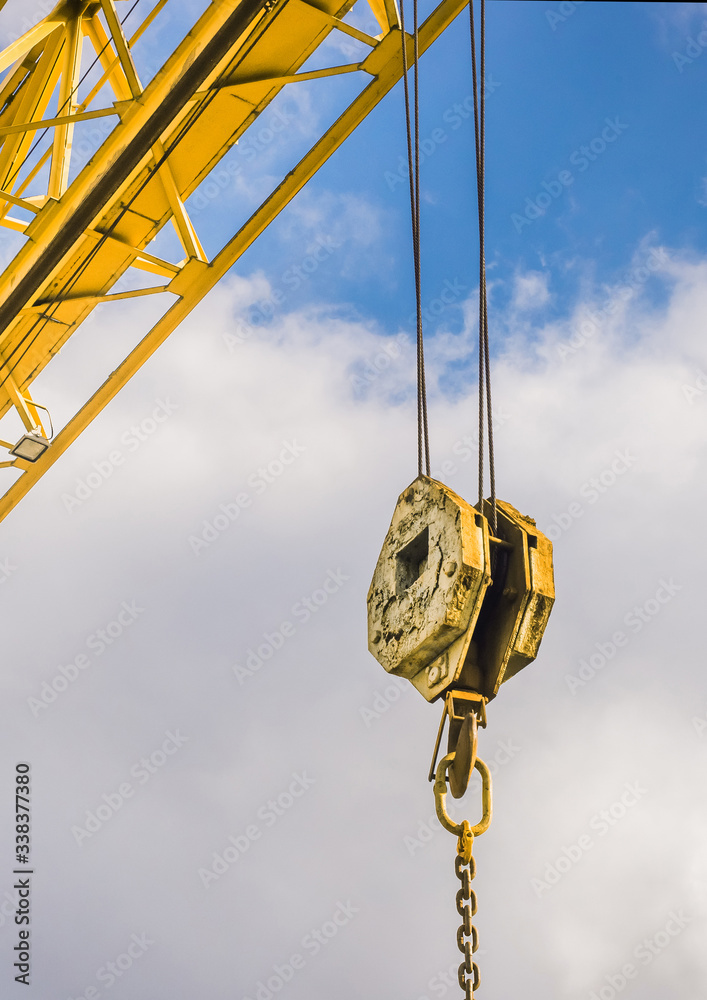 Overhead crane and hook on a background of blue sky with clouds, close-up, bottom view Overhead crane and hook on a background of blue sky with clouds, close-up, bottom view