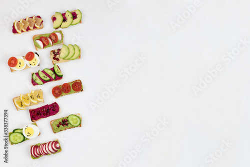 set of different bruschetta sandwiches with beet hummus  guacamole  different vegetables. vegetarian helsifood concept. summer snack. food patern on white background