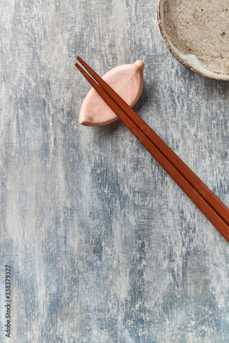 Wooden chopsticks and chopstick rest on rustic wooden background. Top view. Copy space.