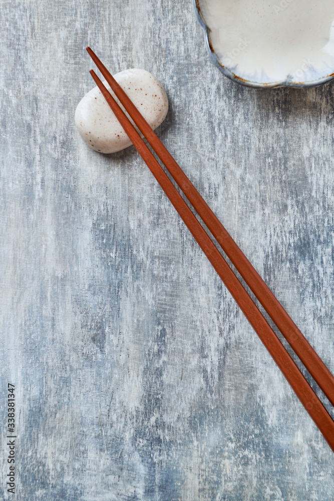 Wooden chopsticks and chopstick rest on rustic wooden background. Top view. Copy space. Wooden chopsticks and chopstick rest on rustic wooden background. Top view. Copy space.