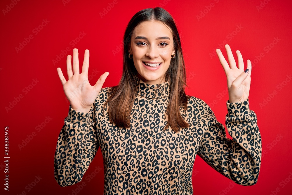 Young beautiful brunette woman wearing casual sweater standing over red background showing and pointing up with fingers number nine while smiling confident and happy. Young beautiful brunette woman wearing casual sweater standing over red background showing and pointing up with fingers number nine while smiling confident and happy.