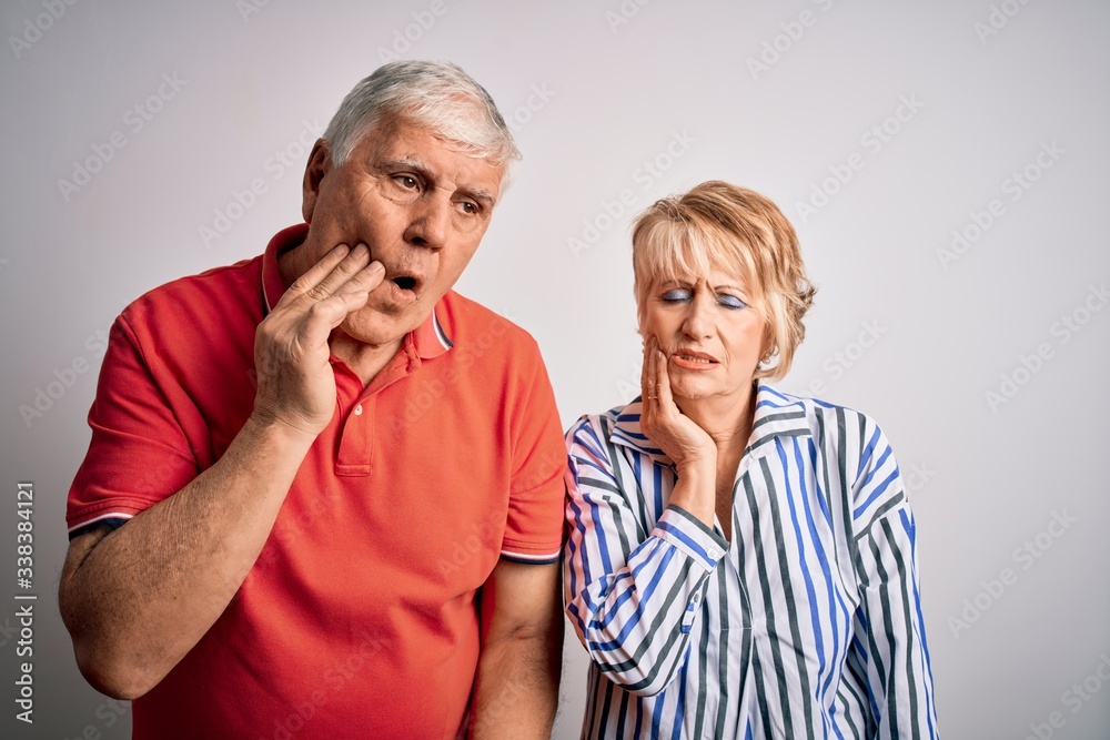 Senior beautiful couple standing together over isolated white background touching mouth with hand with painful expression because of toothache or dental illness on teeth. Dentist Senior beautiful couple standing together over isolated white background touching mouth with hand with painful expression because of toothache or dental illness on teeth. Dentist