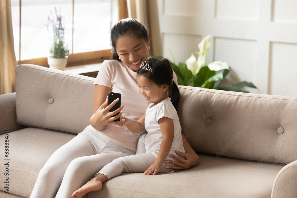 Φωτογραφία Asian mother hold smart phone showing to little daughter entertainment application having fun at home
