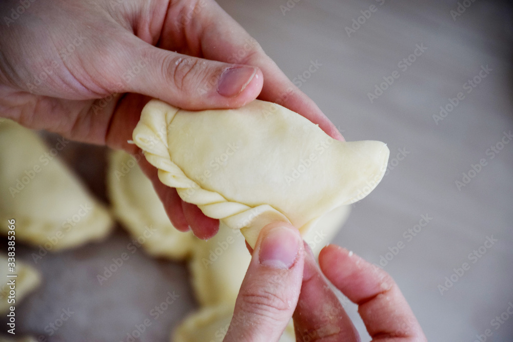 Dumpling vareniki in hand fingers make braid of dough decorating dough Dumpling vareniki in hand fingers make braid of dough decorating dough