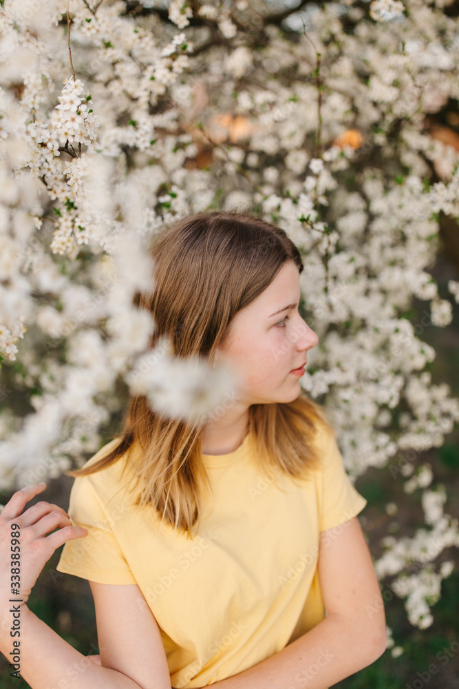 portrait of sad young woman in protective medical face mask with flowers near blooming tree in spring time. Coronavirus protection. epidemic of coronavirus. the aroma a tree in the garden on a spring portrait of sad young woman in protective medical face mask with flowers near blooming tree in spring time. Coronavirus protection. epidemic of coronavirus. the aroma a tree in the garden on a spring