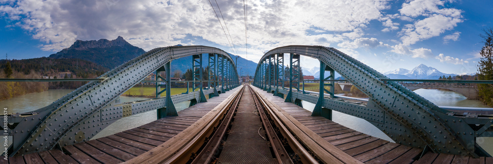 panorama view to old metallic railway bridge with risty rails over rural river lech in austra