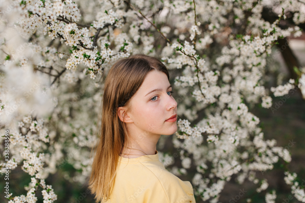 portrait of sad young woman in protective medical face mask with flowers near blooming tree in spring time. Coronavirus protection. epidemic of coronavirus. the aroma a tree in the garden on a spring portrait of sad young woman in protective medical face mask with flowers near blooming tree in spring time. Coronavirus protection. epidemic of coronavirus. the aroma a tree in the garden on a spring