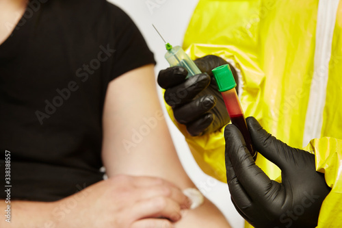 Specialist in virus protective suit holding sterile blood sample secured for testing photo