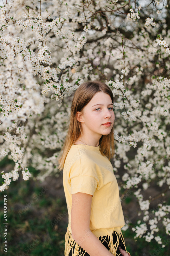 portrait of sad young woman in protective medical face mask with flowers near blooming tree in spring time. Coronavirus protection. epidemic of coronavirus. the aroma a tree in the garden on a spring portrait of sad young woman in protective medical face mask with flowers near blooming tree in spring time. Coronavirus protection. epidemic of coronavirus. the aroma a tree in the garden on a spring