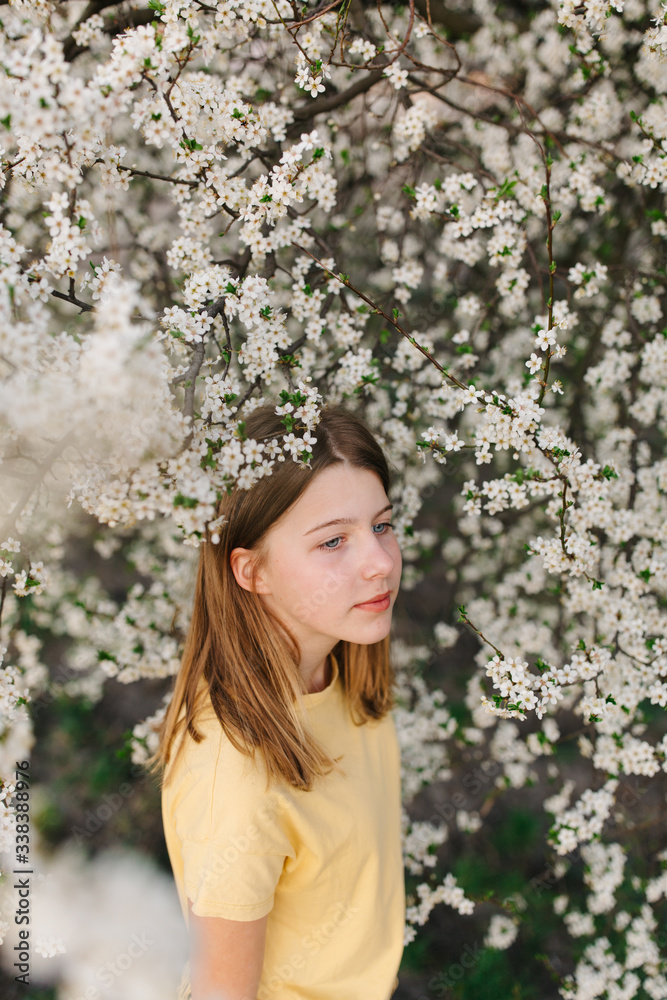 portrait of sad young woman in protective medical face mask with flowers near blooming tree in spring time. Coronavirus protection. epidemic of coronavirus. the aroma a tree in the garden on a spring portrait of sad young woman in protective medical face mask with flowers near blooming tree in spring time. Coronavirus protection. epidemic of coronavirus. the aroma a tree in the garden on a spring