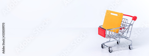 Shopping bags in a silver red shopping cart isolated on white table background, concept of staying home order, close up, copy space design.