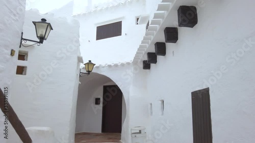 Walking through old traditional menorcan fishing village Binibeca Vell. Narrow streets and charming white houses natural maze. Balearic Island, Menorca coast, Spain. photo