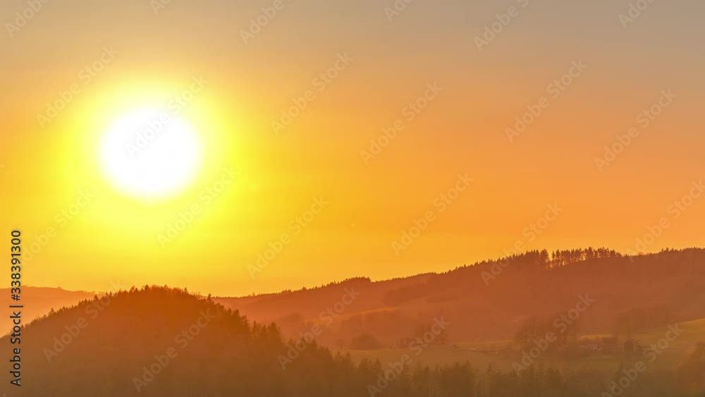 Slowly setting strongly shining sun over the mountains and hills, which slowly shrinks and changes color to the sieve red ball that gradually disappears on the horizon and in the surrounding nature Slowly setting strongly shining sun over the mountains and hills, which slowly shrinks and changes color to the sieve red ball that gradually disappears on the horizon and in the surrounding nature