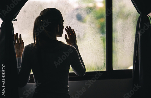 Young Woman Looking Out The Window During Pandemic Quarantine Lockdown